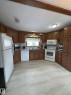 Spacious kitchen featuring extensive wood cabinetry, white appliances, and light-colored flooring - 67 4204 47 Street, Wetaskiwin, AB  - Indoor Photo Showing Kitchen With Double Sink 
