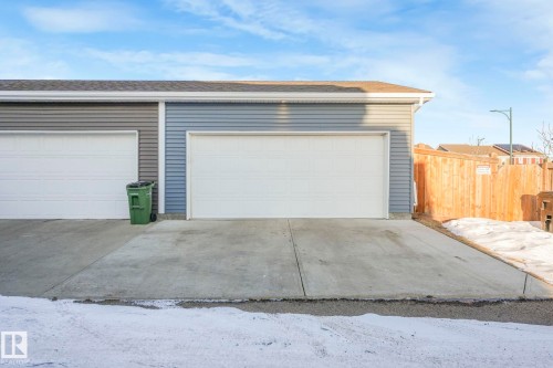 The property features a two-car garage with white garage doors, grey siding, and a concrete driveway - 1920 24 Street, Edmonton, AB - Outdoor