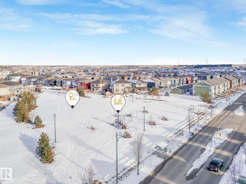 Aerial view of the surrounding neighbourhood, showcasing a large open field, playground equipment, and a residential street with parked cars - 1920 24 Street, Edmonton, AB - Outdoor With View