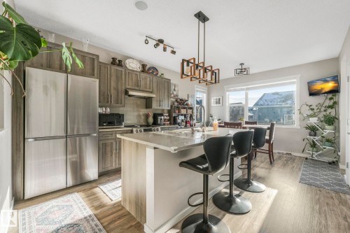 The kitchen features modern wood-look cabinetry, stainless steel appliances, and a central island with a light-colored countertop - 1920 24 Street, Edmonton, AB - Indoor Photo Showing Kitchen With Upgraded Kitchen