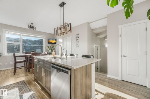 Open concept kitchen and dining area featuring a kitchen island with seating, stainless steel appliances, and large windows - 1920 24 Street, Edmonton, AB - Indoor Photo Showing Kitchen