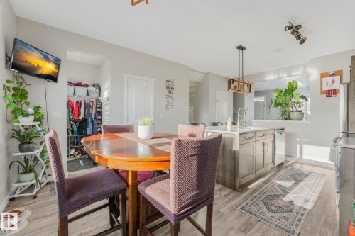 The property features an open living space with light-colored walls, a wooden dining table, and a kitchen island with a sink and light-toned cabinetry - 1920 24 Street, Edmonton, AB - Indoor Photo Showing Dining Room