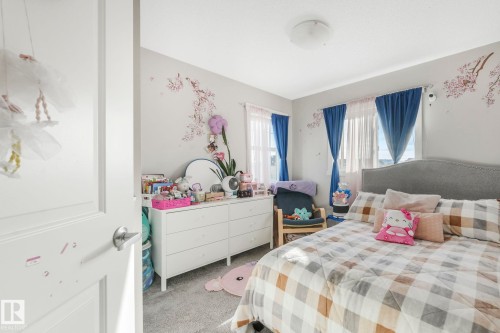 Bedroom featuring light gray walls, carpet flooring, and a large window with blue curtains - 1920 24 Street, Edmonton, AB - Indoor Photo Showing Bedroom