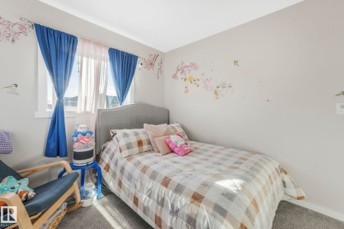 This room features a window with blue curtains and sheer panels, a bed with a gray upholstered headboard, and light-colored walls - 1920 24 Street, Edmonton, AB - Indoor Photo Showing Bedroom