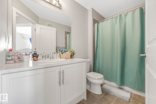 The bathroom features a vanity with a white countertop and a drop-in sink, a toilet, and a shower area with a curtain - 1920 24 Street, Edmonton, AB - Indoor Photo Showing Bathroom