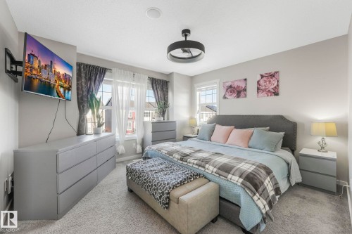 This inviting room features soft gray carpeting, a ceiling-mounted light fixture, and windows with curtains providing natural light - 1920 24 Street, Edmonton, AB - Indoor Photo Showing Bedroom