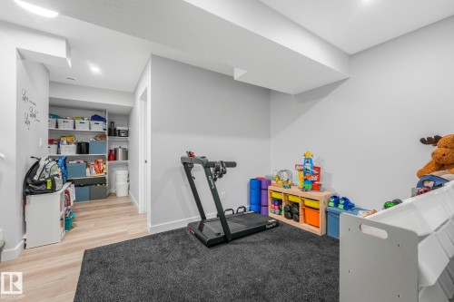 This versatile room features light-colored walls, a dark grey carpeted area, and light wood-look flooring - 1920 24 Street, Edmonton, AB - Indoor Photo Showing Gym Room