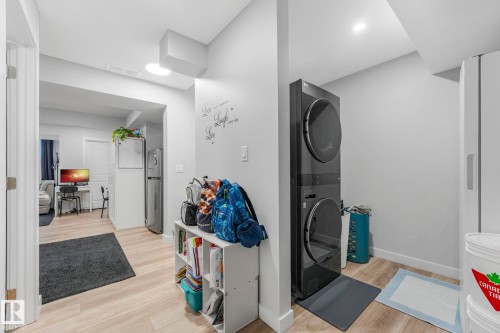 The property features a laundry area with a stacked washer and dryer, light wood-style flooring, and recessed lighting - 1920 24 Street, Edmonton, AB - Indoor