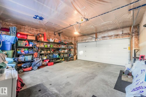 The property features a garage with a concrete floor, exposed wood beam walls, and a large white garage door - 1920 24 Street, Edmonton, AB - Indoor Photo Showing Garage
