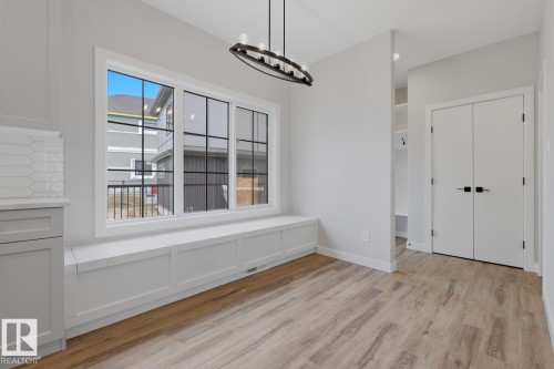 Built-in window seat with storage, large multi-pane window, wood-finish flooring, built-in shelving, and bi-fold doors with black hardware - 30 Chartres Close Nw, St. Albert, AB 