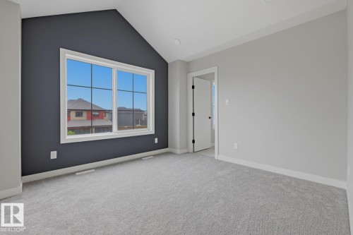 Spacious interior room featuring a large window with white trim, a vaulted ceiling, and a dark accent wall - 30 Chartres Close Nw, St. Albert, AB 