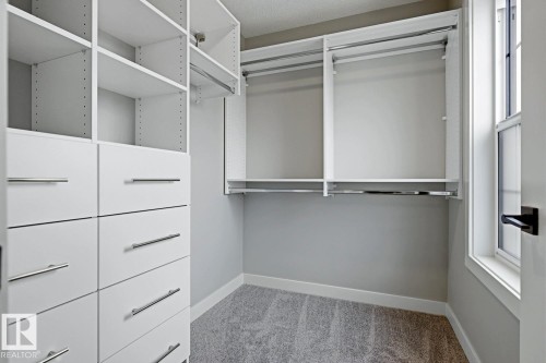 Custom closet system featuring white cabinetry, multiple shelving units, integrated drawers with brushed nickel hardware, and dual hanging rods - 30 Chartres Close Nw, St. Albert, AB 