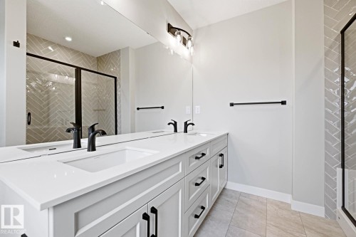 Double vanity with integrated sinks, white countertops, matte black fixtures, and extensive under-sink storage - 30 Chartres Close Nw, St. Albert, AB 