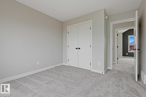 Light gray wall color with white trim, soft gray carpeting, and a white bi-fold closet with matte black hardware - 30 Chartres Close Nw, St. Albert, AB 