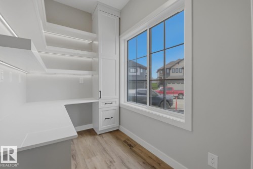 Dedicated workspace featuring white cabinetry, integrated shelving with accent lighting, and a white countertop - 30 Chartres Close Nw, St. Albert, AB 