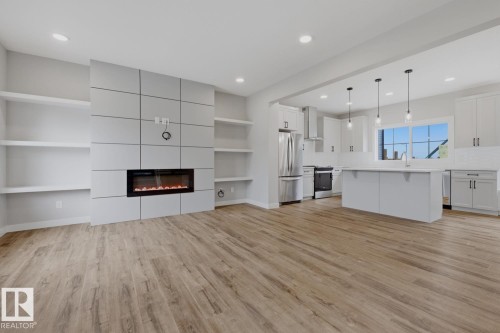 Open-concept living space featuring wood-finish flooring, a modern electric fireplace, built-in shelving, and recessed lighting - 30 Chartres Close Nw, St. Albert, AB 