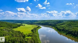 Expansive river setting with a lush green floodplain, surrounded by dense woodland - 