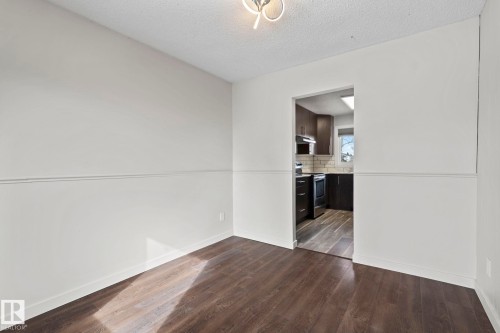 This room features dark wood-style flooring and light-colored walls with wainscoting detail - 18124 68Ave, Edmonton, AB - Indoor Photo Showing Other Room