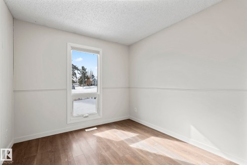 This room features hardwood style flooring, white walls, and a window providing natural light - 18124 68Ave, Edmonton, AB - Indoor Photo Showing Other Room