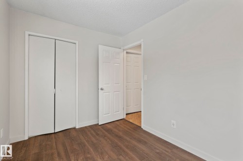 This room features wood-look flooring and white walls, creating a neutral backdrop - 18124 68Ave, Edmonton, AB - Indoor Photo Showing Other Room