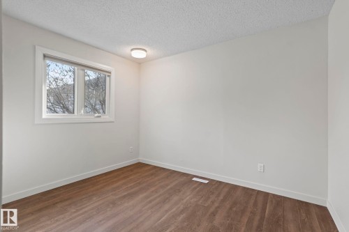 This room features durable plank flooring, a window offering natural light, and a ceiling-mounted light fixture - 18124 68Ave, Edmonton, AB - Indoor Photo Showing Other Room