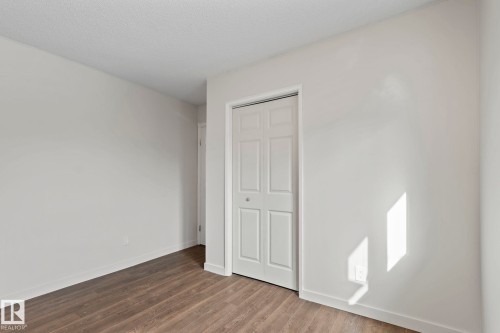 This room features wood-look flooring and a white bi-fold closet door - 18124 68Ave, Edmonton, AB - Indoor Photo Showing Other Room