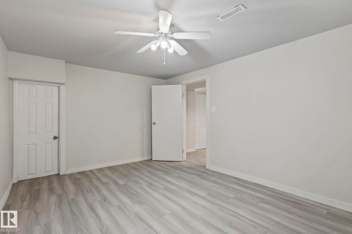 This room features light-toned flooring, white walls, and a ceiling fan with integrated lighting - 18124 68Ave, Edmonton, AB - Indoor Photo Showing Other Room