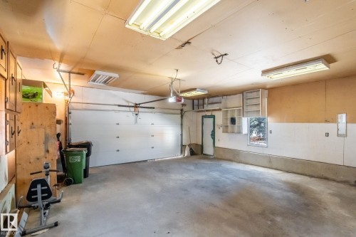 This garage features a concrete floor, a garage door, and overhead fluorescent lighting - 18124 68Ave, Edmonton, AB - Indoor Photo Showing Garage