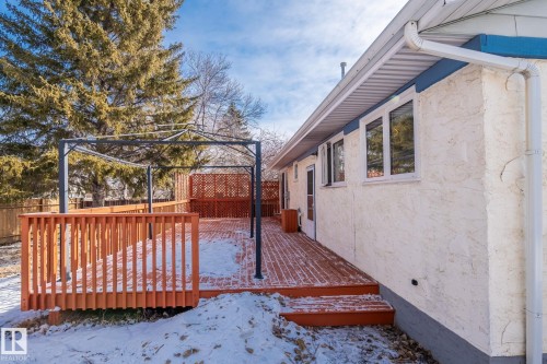 The property features a spacious wooden deck, partially covered by a metal pergola structure - 18124 68Ave, Edmonton, AB - Outdoor