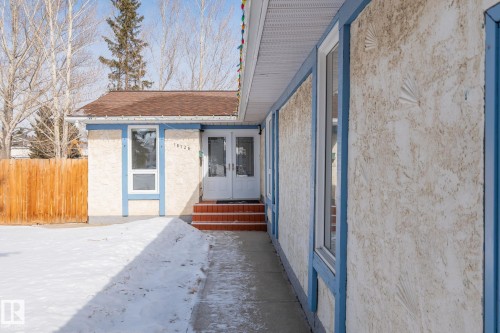The property features an exterior with textured stucco siding and blue trim around the windows and roofline - 18124 68Ave, Edmonton, AB - Outdoor