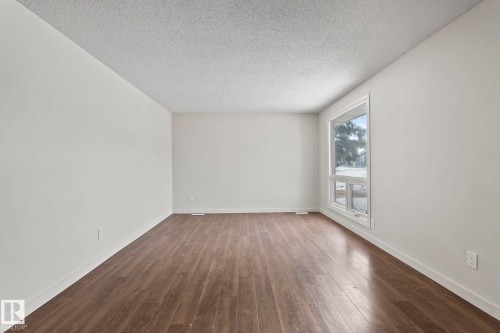 This room features hardwood style flooring and a large window - 18124 68Ave, Edmonton, AB - Indoor Photo Showing Other Room