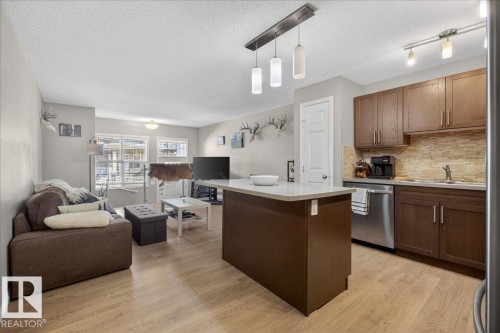 Open concept living area featuring light wood-style flooring, a kitchen island with a light-colored countertop, and recessed lighting - 33 4029 Orchards Drive Sw, Edmonton, AB - Indoor Photo Showing Kitchen