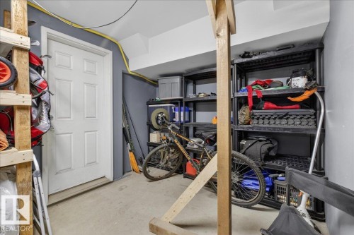 This space features concrete flooring and a paneled white door, with a ceiling and walls painted in contrasting tones - 33 4029 Orchards Drive Sw, Edmonton, AB - Indoor