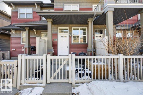 The property features a red facade with horizontal siding and grey trim - 33 4029 Orchards Drive Sw, Edmonton, AB - Outdoor With Deck Patio Veranda With Facade
