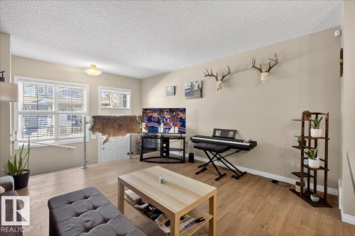 Living area featuring light-colored walls, light wood-style flooring, and white window blinds - 33 4029 Orchards Drive Sw, Edmonton, AB - Indoor Photo Showing Living Room