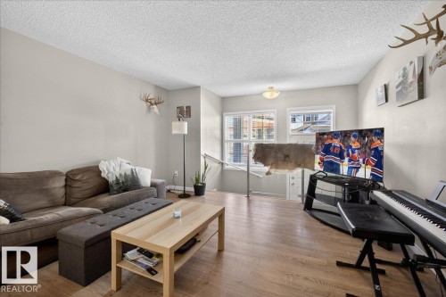 The living area features light-toned walls, hardwood flooring, and multiple windows providing natural illumination - 33 4029 Orchards Drive Sw, Edmonton, AB - Indoor Photo Showing Living Room
