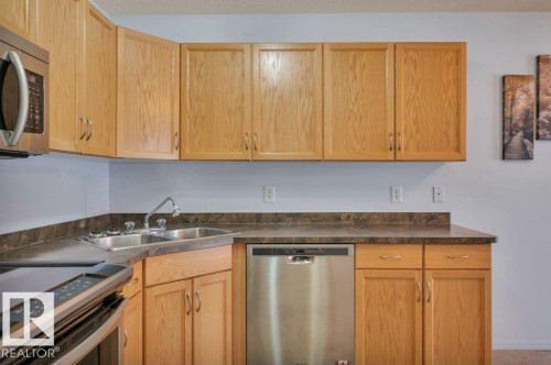 The kitchen features light-toned wooden cabinetry and dark countertops - 103 309 Clareview Station Drive, Edmonton, AB - Indoor Photo Showing Kitchen With Double Sink
