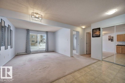 The living area features a sliding glass door, providing access to the exterior, and is illuminated by a contemporary ceiling light fixture - 103 309 Clareview Station Drive, Edmonton, AB - Indoor Photo Showing Other Room