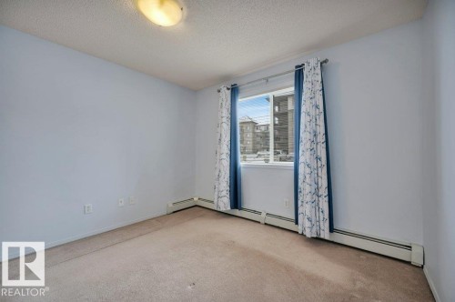 The room features a window with curtains, light blue walls, and carpeting - 103 309 Clareview Station Drive, Edmonton, AB - Indoor Photo Showing Other Room