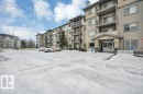 The property features a multi-story building with balconies, an entrance with an overhang, and an exterior of siding and stone accents - 103 309 Clareview Station Drive, Edmonton, AB  - Outdoor With Balcony With Facade 