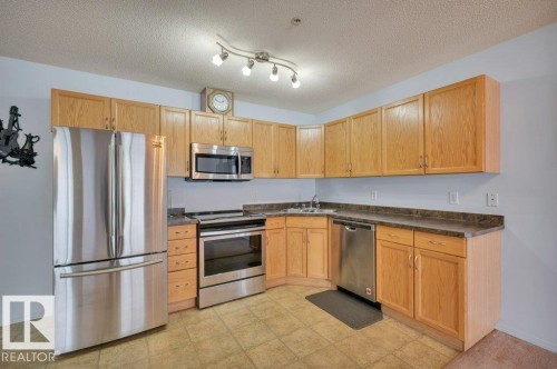 Kitchen featuring light wood cabinetry, stainless steel appliances, a tile floor, and track lighting - 103 309 Clareview Station Drive, Edmonton, AB - Indoor Photo Showing Kitchen