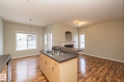 Kitchen featuring dark countertops, open floor plan, pendant lighting, a fireplace, and light wood-type flooring - 