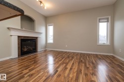 Unfurnished living room featuring dark wood-type flooring and a tiled fireplace - 