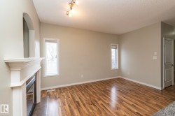 Unfurnished living room featuring dark wood-style flooring, a tile fireplace, plenty of natural light, and a textured ceiling - 