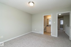 Unfurnished bedroom featuring a textured ceiling, light carpet, and ensuite bathroom - 