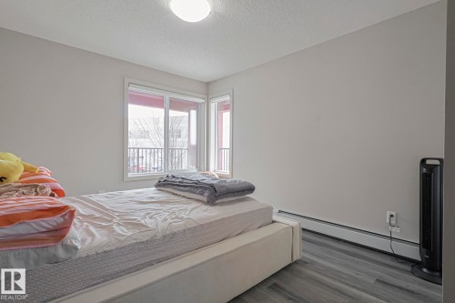 Bedroom featuring a baseboard heating unit, a textured ceiling, and dark wood finished floors - 236 344 Windermere Road, Edmonton, AB - Indoor Photo Showing Bedroom