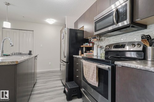 Kitchen with stainless steel appliances, light countertops, tasteful backsplash, a textured ceiling, and light wood finished floors - 236 344 Windermere Road, Edmonton, AB - Indoor Photo Showing Kitchen With Stainless Steel Kitchen With Upgraded Kitchen