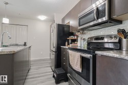 Kitchen with stainless steel appliances, light countertops, tasteful backsplash, a textured ceiling, and light wood finished floors - 