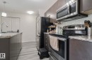 Kitchen with stainless steel appliances, light countertops, tasteful backsplash, a textured ceiling, and light wood finished floors - 236 344 Windermere Road, Edmonton, AB  - Indoor Photo Showing Kitchen With Stainless Steel Kitchen With Upgraded Kitchen 