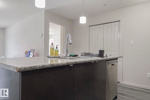 Kitchen featuring an island with sink, light countertops, stainless steel dishwasher, and dark wood-style floors - 236 344 Windermere Road, Edmonton, AB - Indoor